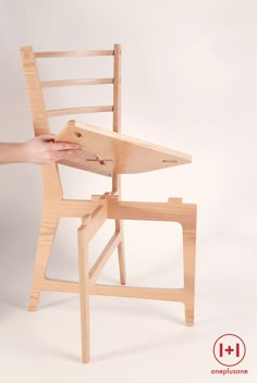 a hand is holding the edge of a chair that has been made out of wood