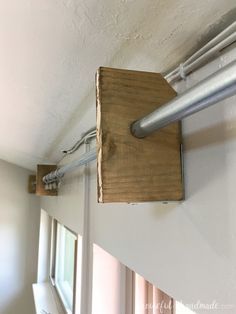 a wooden object is hanging on the side of a wall in a room with white walls