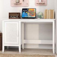 a white desk with a laptop on top of it next to some books and other items