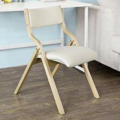 a white chair sitting on top of a hard wood floor next to a desk with a laptop computer