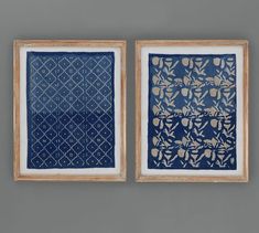 two blue and white paintings hanging on the wall next to each other, one with gold leaf designs