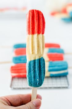 a hand holding a popsicle with red, white and blue frosting