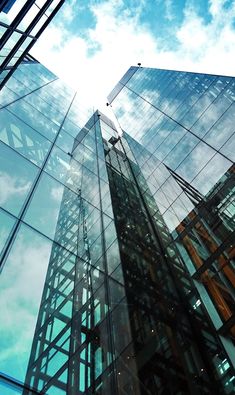 some very tall buildings with glass windows on the sides and sky in the back ground