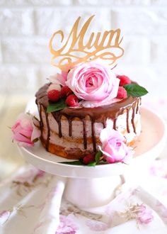 a cake on a plate with pink flowers and a gold monogrammed top that says mum