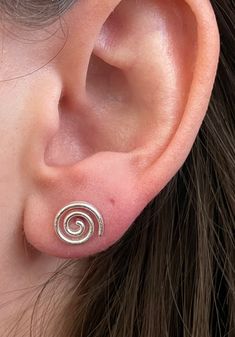 Beautiful textured 925 Sterling Silver Spiral stud earrings. These push back studs look amazing in all light with their delicately brushed finish. Metaphysical Benefits: The spiral is the rhythm of life. It characterizes the creative vital force of human and society, a symbol of unity of generations, and spiritual and moral growth of man. It means the life order, the symbol of continuity, development, motion, and journey into the unknown. Spiral Stud Earrings, Cute Unique Earrings, Cute Studs Earrings, Uneven Ear Piercings, Pretty Silver Earrings, Gold Spiral Jewelry, Ear Piercings Grunge, Spiral Symbol Meaning, Cool Silver Jewelry