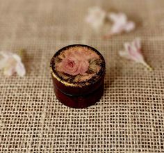 a small wooden box sitting on top of a burlied tablecloth covered in flowers