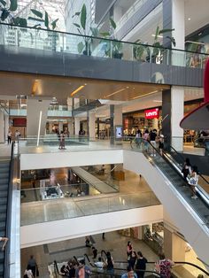 people are walking up and down the escalator in a shopping mall with their luggage