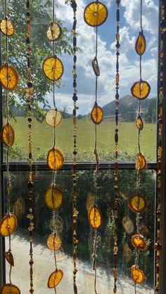 a window with some glass beads hanging from it's side and trees in the background