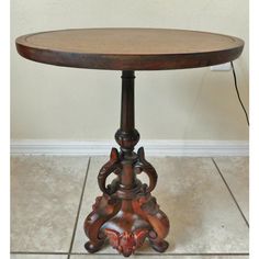 an old wooden table with carvings on the top and bottom, sitting on tile flooring