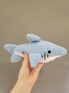 a hand holding a small stuffed shark toy