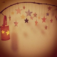 a red bag hanging from the side of a string with stars attached to it, in front of a white wall