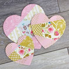 three heart shaped paper pieces sitting on top of a wooden floor