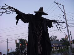 a scarecrow standing in the street with his arms outstretched and hands out to the side