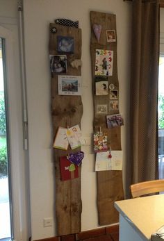 a wall with pictures and magnets on it next to a kitchen counter top in front of a sliding glass door