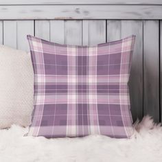 a purple plaid pillow sitting on top of a white fur rug