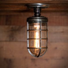 an old fashioned light fixture hanging from a wooden ceiling over a wood paneled wall