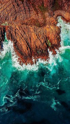 an aerial view of the ocean and rocks