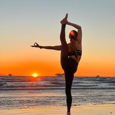 a woman doing yoga on the beach at sunset