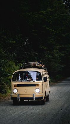 an old vw van with luggage strapped to the roof is driving down a road