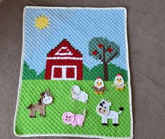 a crocheted placemat with farm animals on it and a barn in the background