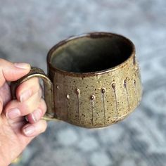 a person holding a coffee mug with water dripping from the inside and outside, in their left hand