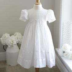 a white dress on a mannequin next to flowers