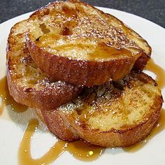 two pieces of french toast on a plate with syrup drizzled around them