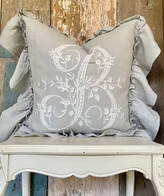 a white chair with a gray pillow on it and a wooden wall in the background