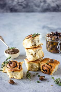 several rolls stacked on top of each other with olives in the bowl next to them