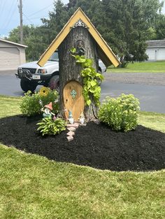 a fairy house made out of a tree stump in the middle of a yard with black mulch