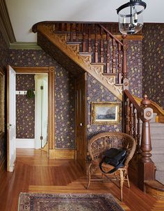 a dog laying on the floor in front of a stair case next to a chair