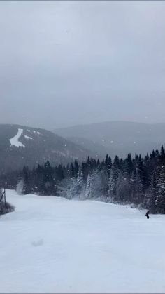 a snow covered ski slope with trees in the background