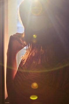 the back of a woman's head as she stands in front of a window