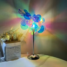 a colorful lamp sitting on top of a table next to a vase filled with flowers