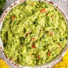 a bowl filled with guacamole next to corn