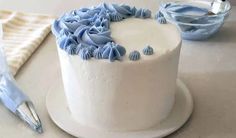 a white cake with blue icing on a plate next to a knife and napkin