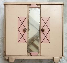 an old pink and white cabinet with mirrors on it