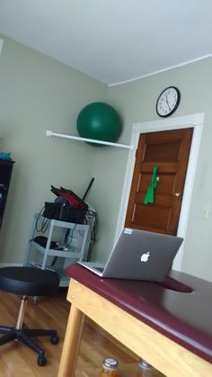 an open laptop computer sitting on top of a wooden desk in front of a doorway