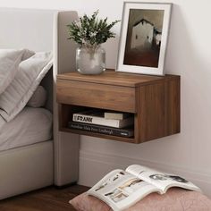 a nightstand with a book and vase on it