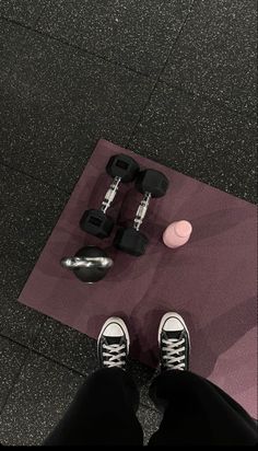 a person standing on top of a purple mat next to dumbbells and a pair of sneakers