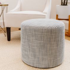 a white chair sitting next to a ottoman in a living room on top of a rug