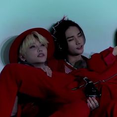 two women in red outfits are laying on the floor with their arms around each other