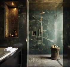 a bathroom with a glass shower stall and black marble walls, along with a white bathtub