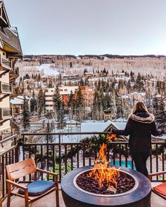 a woman standing on top of a balcony next to a fire pit