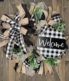 a welcome wreath with black and white plaid ribbon