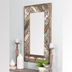 a mirror sitting on top of a wooden shelf next to a vase and candle holder