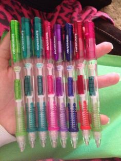 a person holding a bunch of pens in their hand with different colors and shapes on them