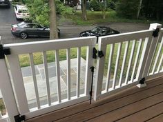 two cars parked on the side of a road next to a white fence and wooden deck