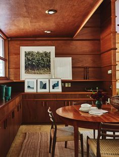 a dining room table with chairs and pictures hanging on the wall above it, in front of a window