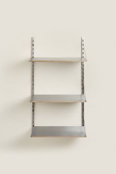 three metal shelving shelves on the wall with one empty shelf in front of them